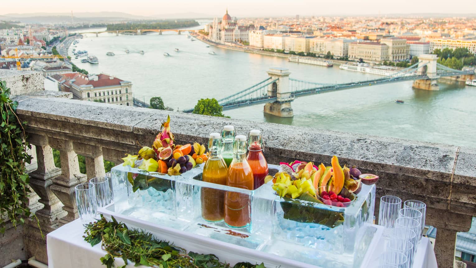 Juices and tropical fruit on table on balcony of Buda Castle overlooking river