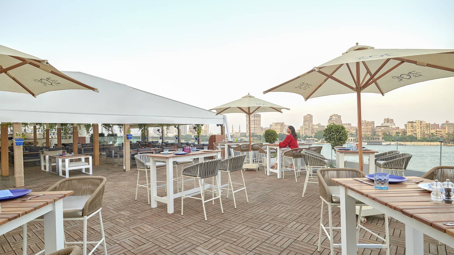 Woman in red dress seated at dining table on Zoe restaurant terrace over Nile views