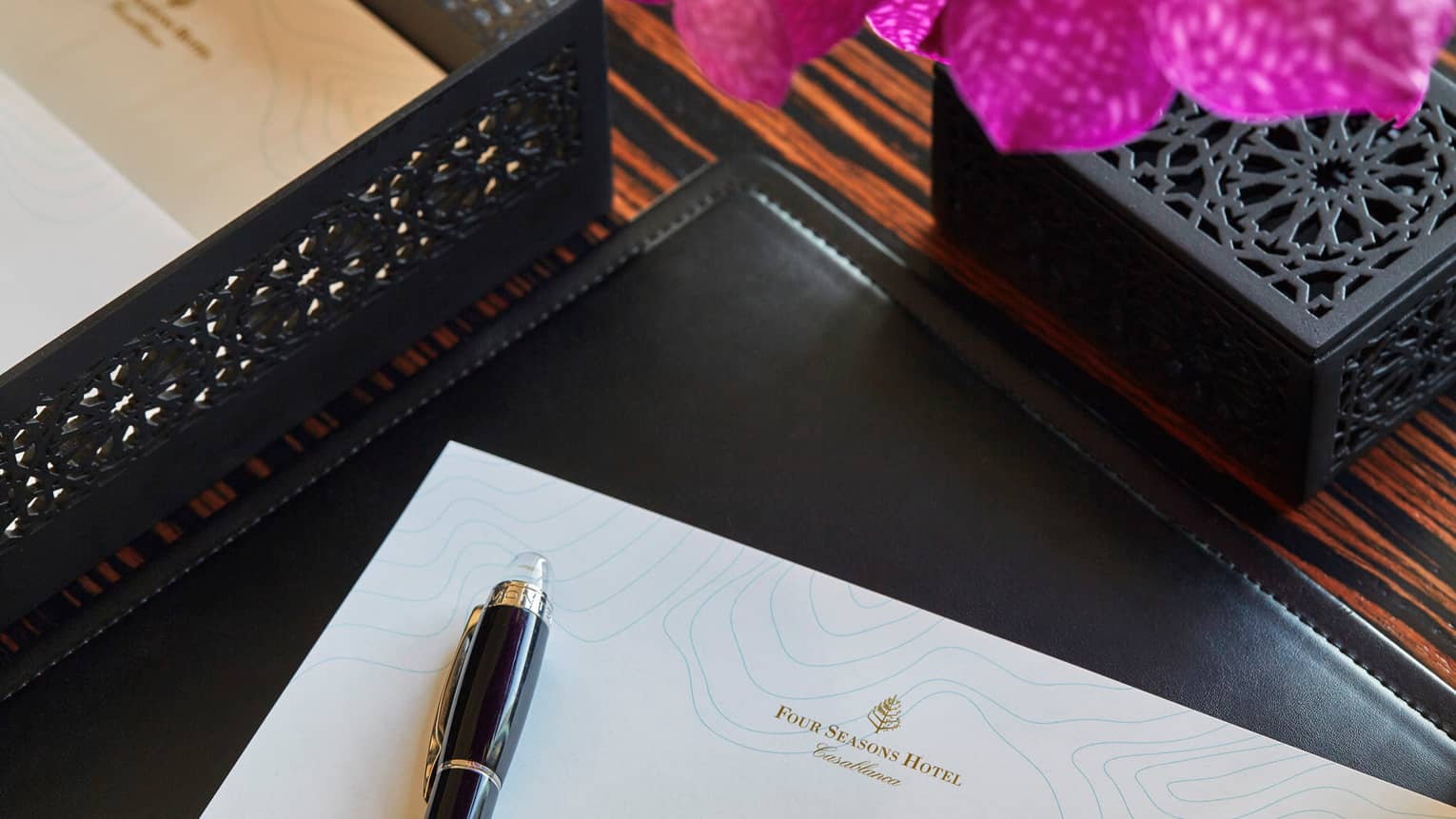 Corner of white piece of paper with Four Seasons logo, pen