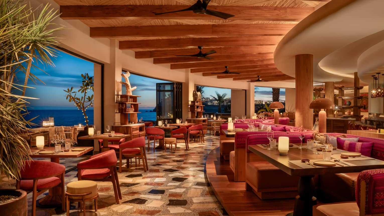 Interior, curved edge of resort restaurant with indoor-outdoor seating and ocean view