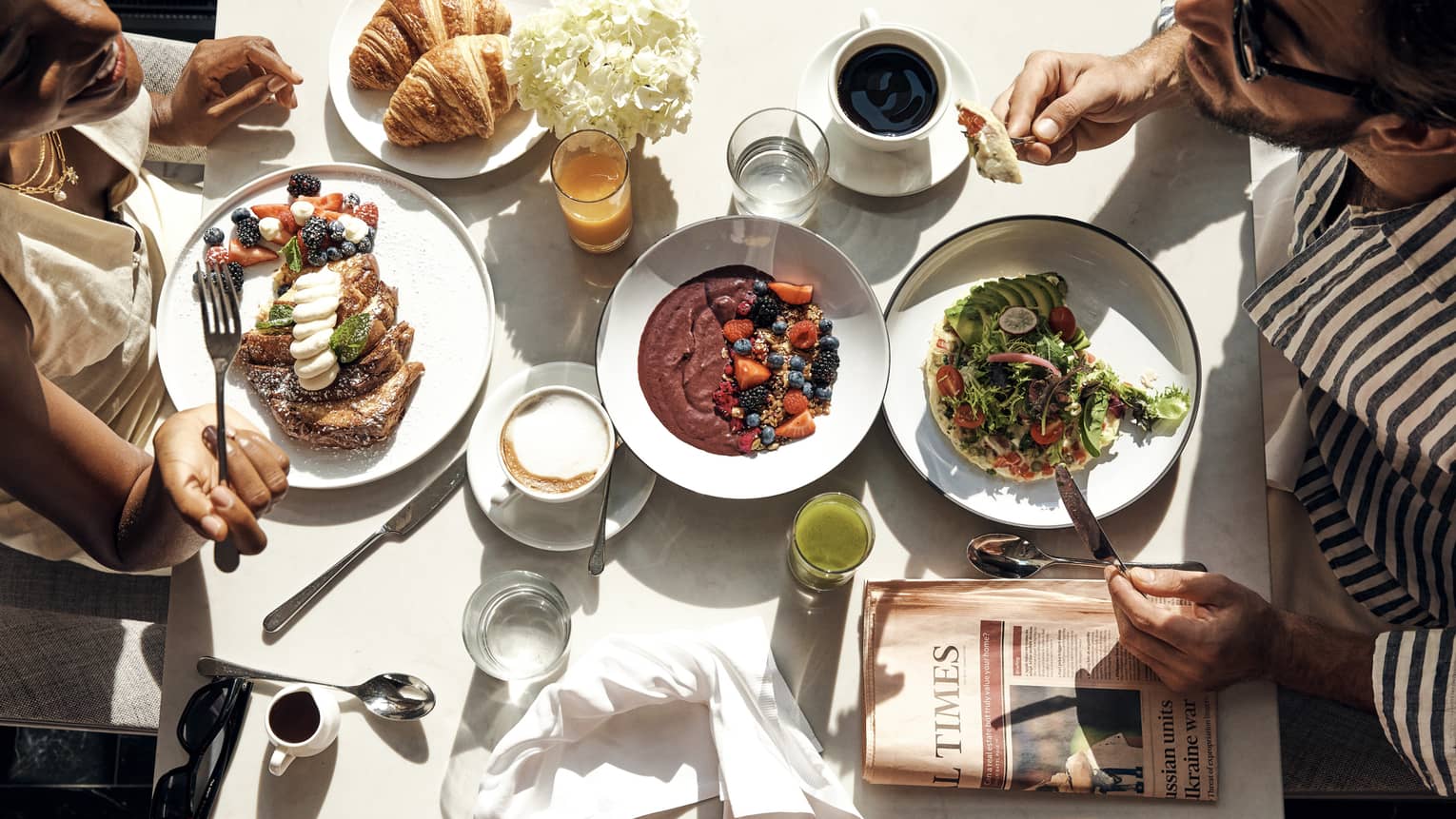 Two people eating food at a white table.