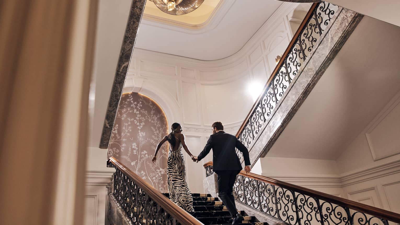 A man and woman in fine clothing walking up stairs.