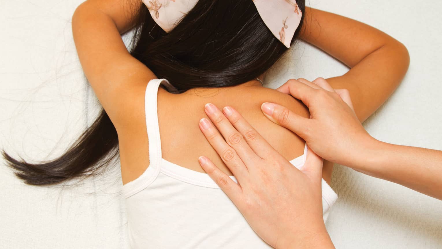 Masseuse hands massage girl's shoulders