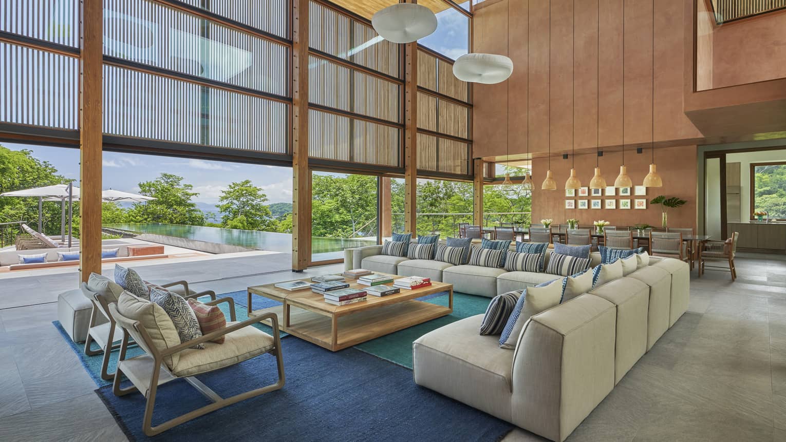 Large living room with extra-high ceilings, large sectional sofa and two chairs, entrance to outside pool deck