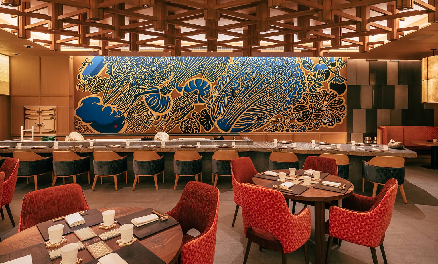 Restaurant dining room with a long rectangular communal table and various round tables set for four