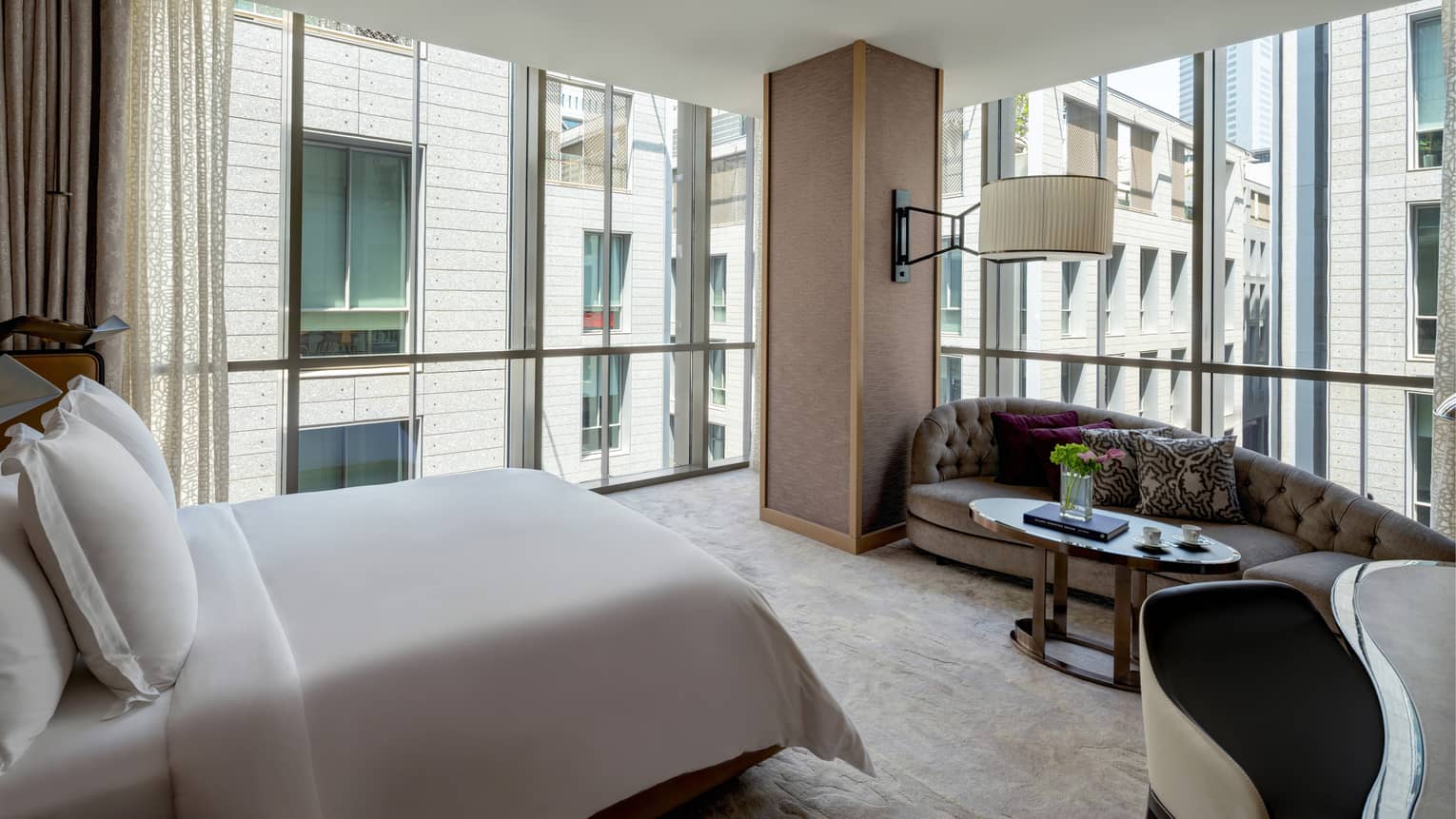 Corner bedroom with walls of windows, king bed and chaise