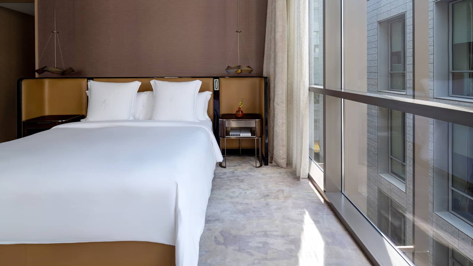 King bed with white sheets and wall of windows