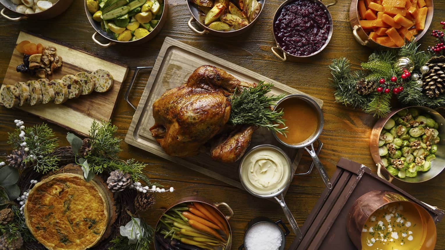 A full festive feast with a Turkey in the centre, and several copper pots of stewed vegetables surrounding