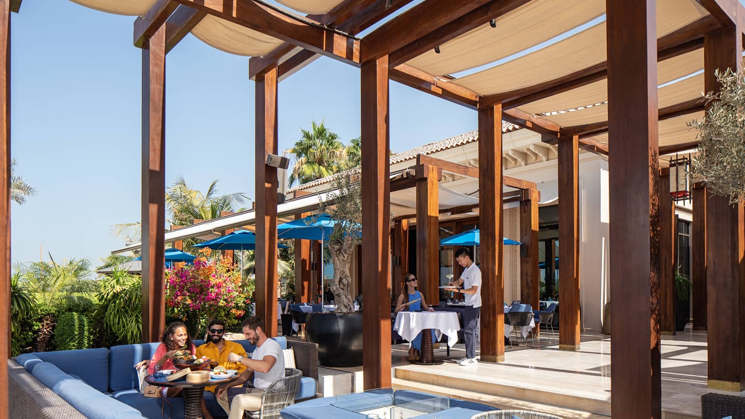 Several people dine outside in a covered patio.