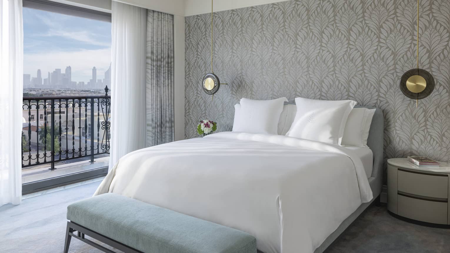 Hotel room with king bed, light blue bench and small balcony with Dubai view