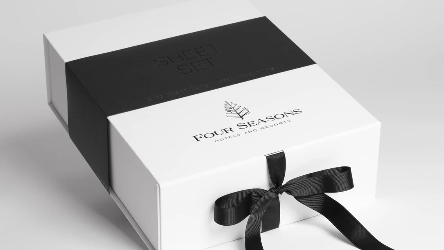 A white four seasons gift card packaging with a black ribbon tied around it