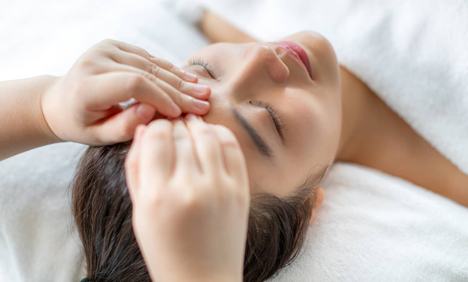 A woman getting a facial massage in a spa.