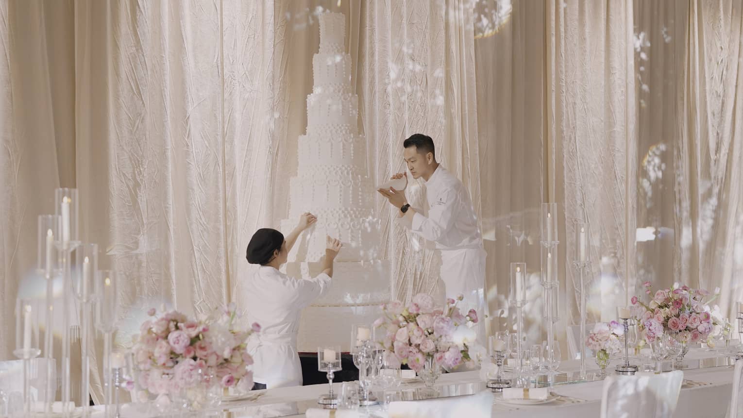 Man and woman put finishing touches on an extra-tall wedding cake