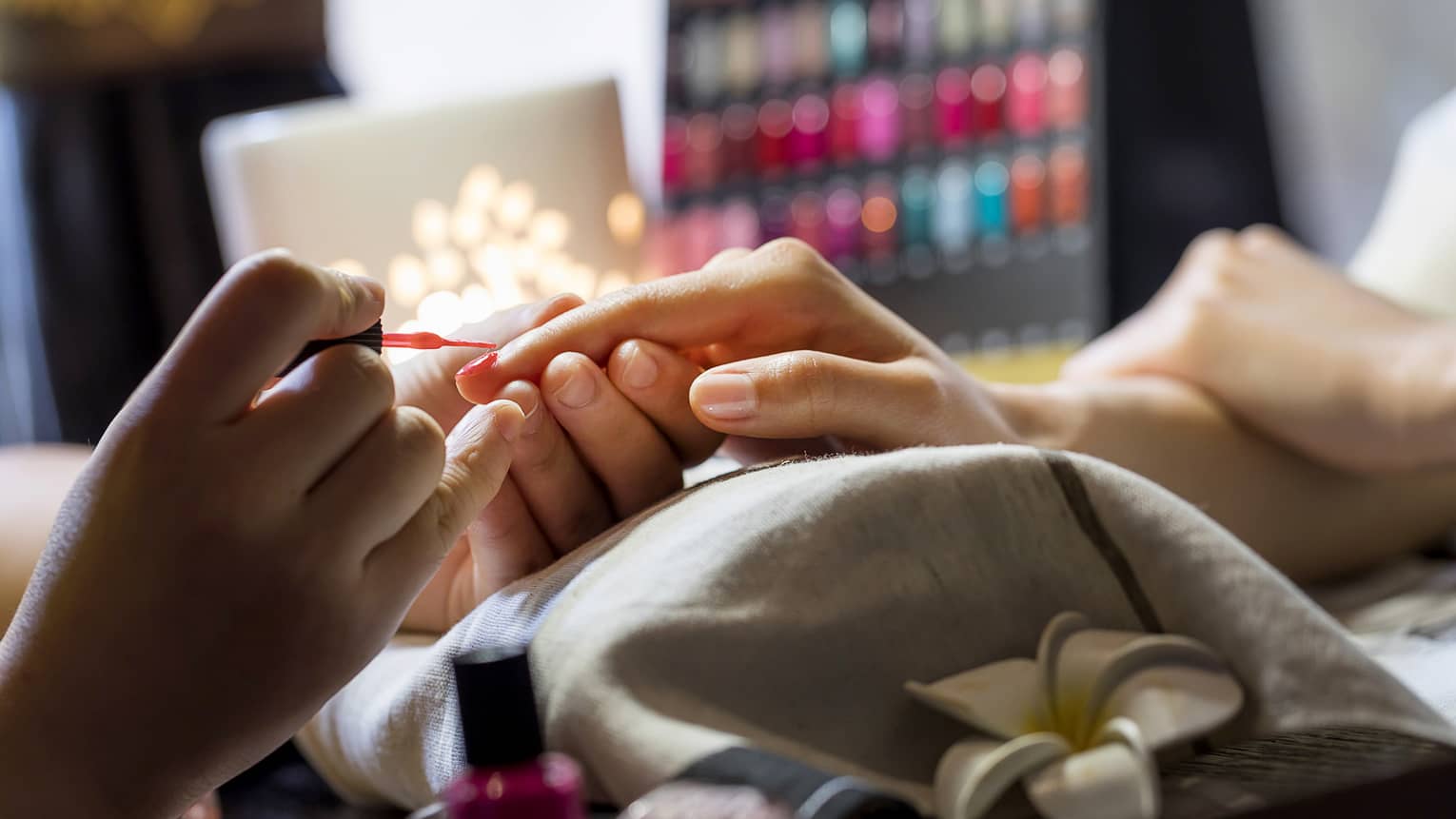 Close-up of manicure, hands resting on pillow as nails painted