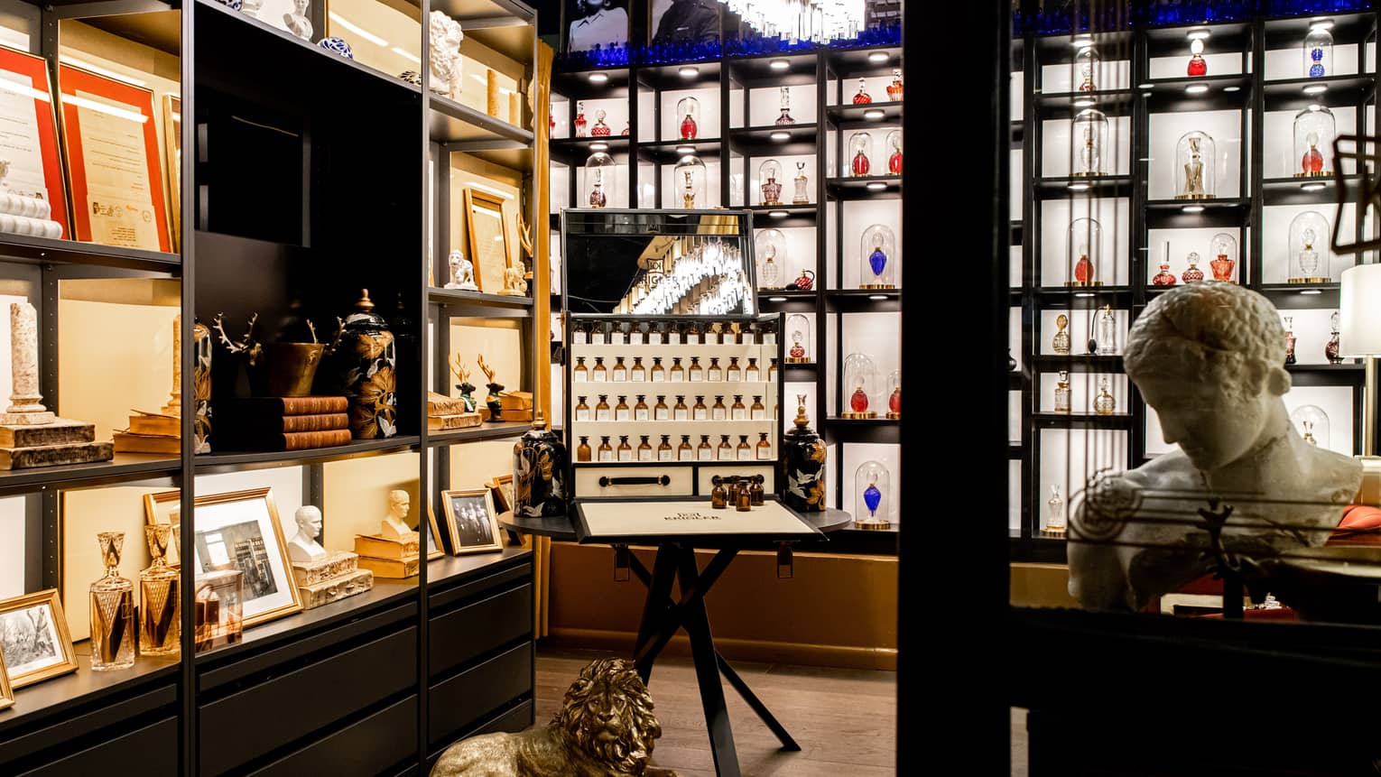Store with various perfumes on display and a small marble sculpture.