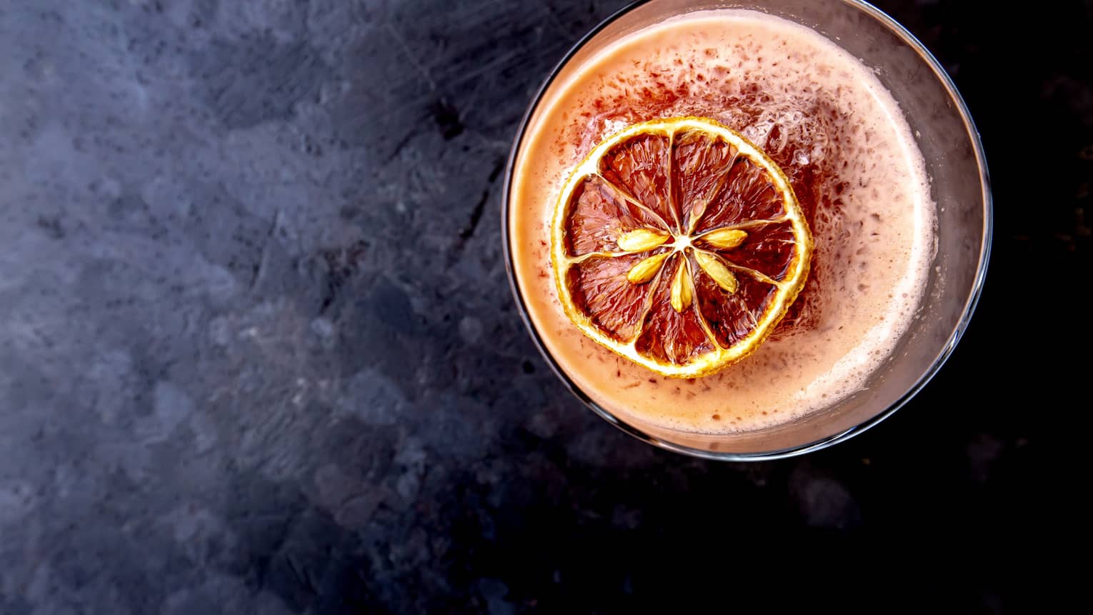 An orange cocktail with a slide of orange floating on top.