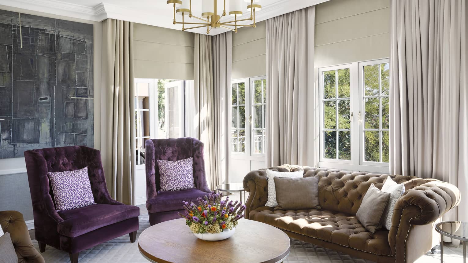 Luxury hotel suite living room with two violet velvet chairs and brown tufted sofa at Four Seasons Hotel Johannesburg
