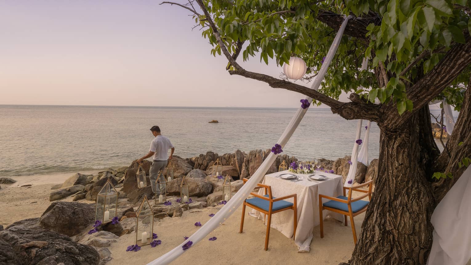 Staff member preps beachside table for intimate wedding dinner