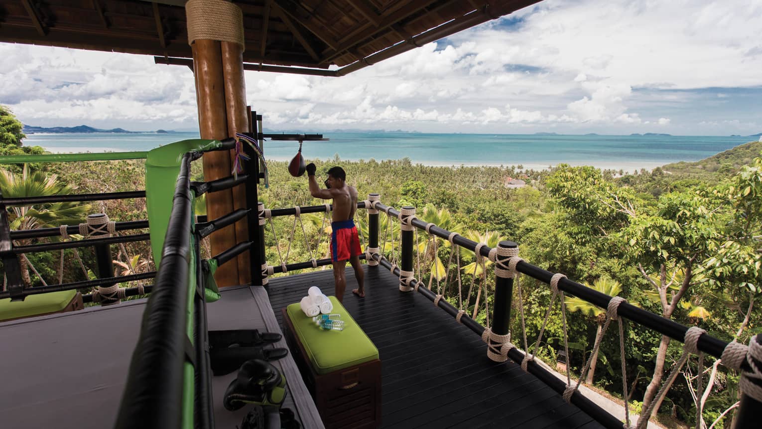 Muay Thai boxer in corner of balcony high above tropical forests