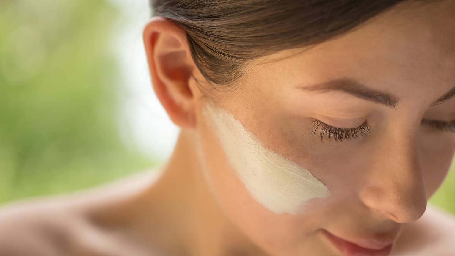 Close-up of side of woman's face with lotion on cheek