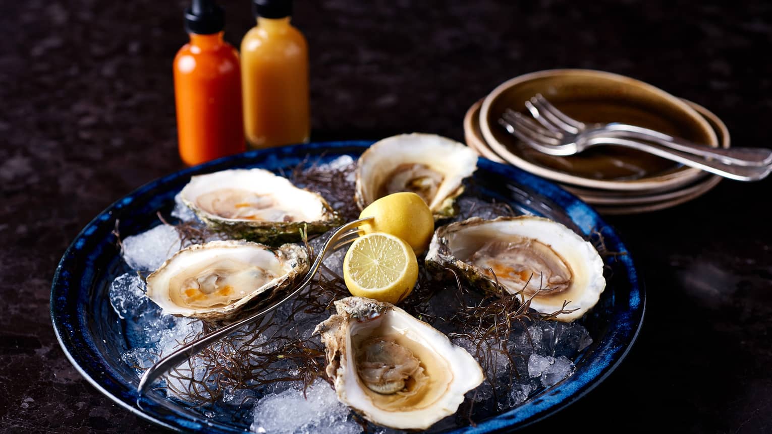 Plate of half shell oysters, lemons on ice 