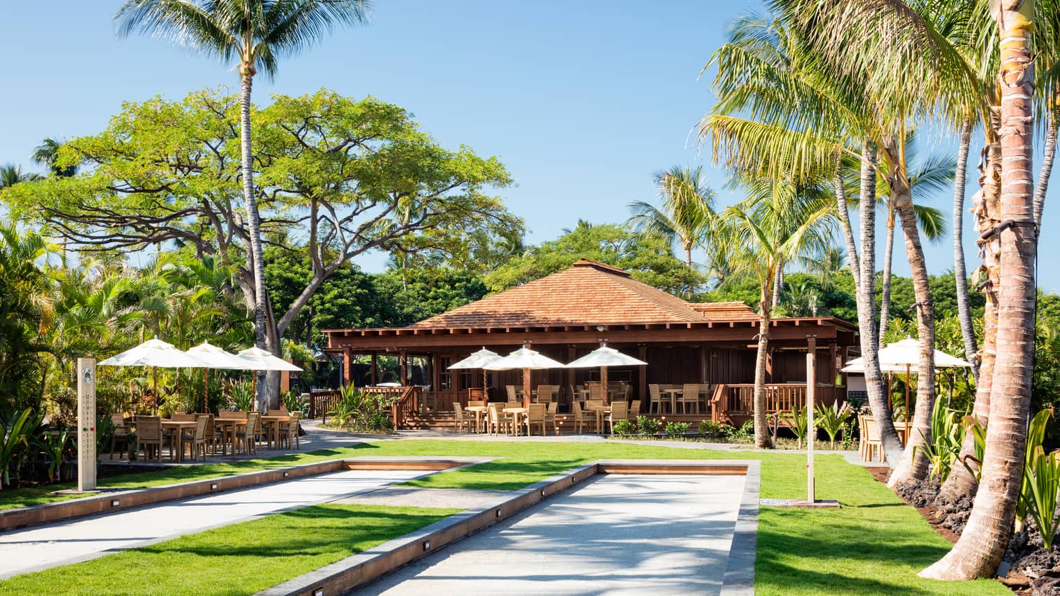 Two Bocce courts and cafe with outdoor terrace in a tropical setting with palm trees