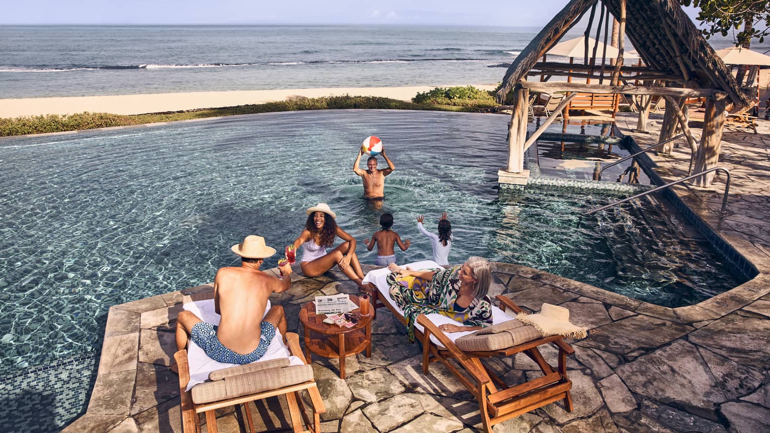 People relax at an oceanside pool at tropical resort