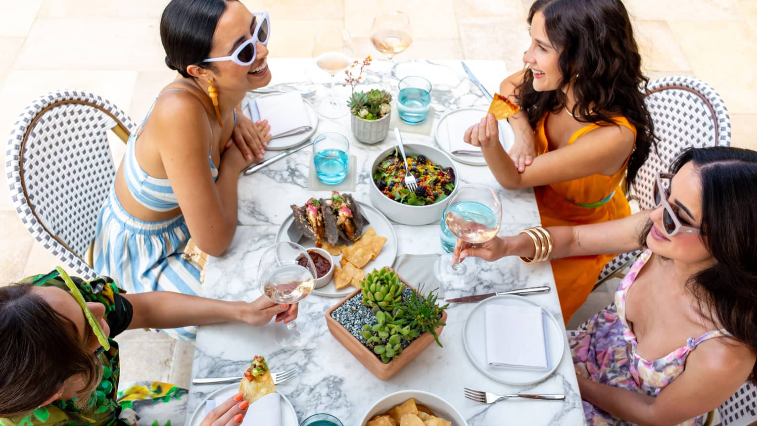 Group of four women dine at outdoor restaurant table