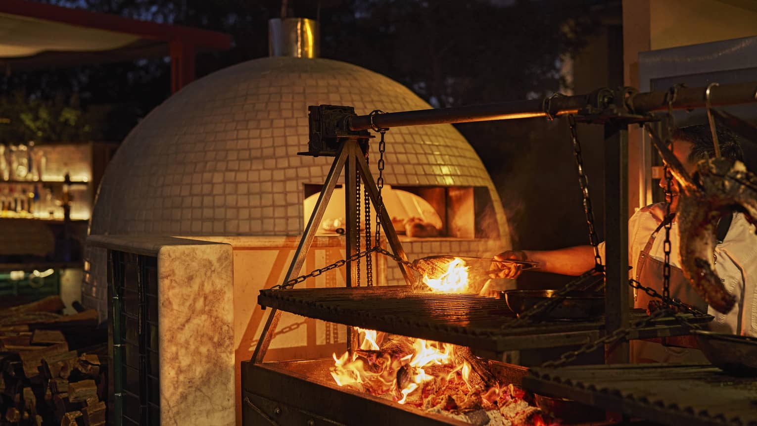 Wood-fired pizza oven and open fire in outdoor kitchen
