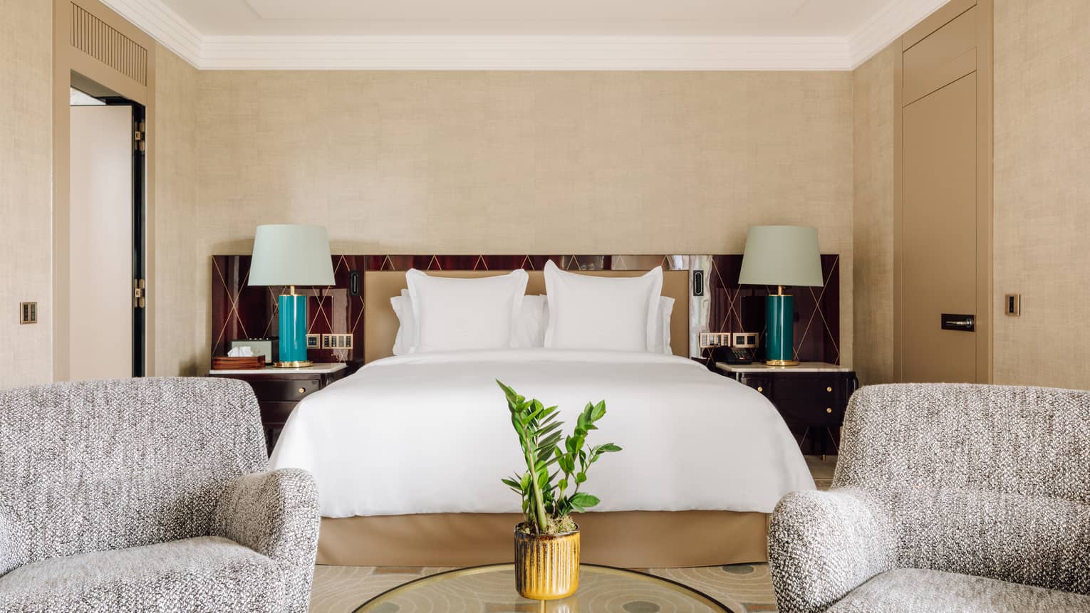 Bedroom with king bed, two lamps and two arm chairs