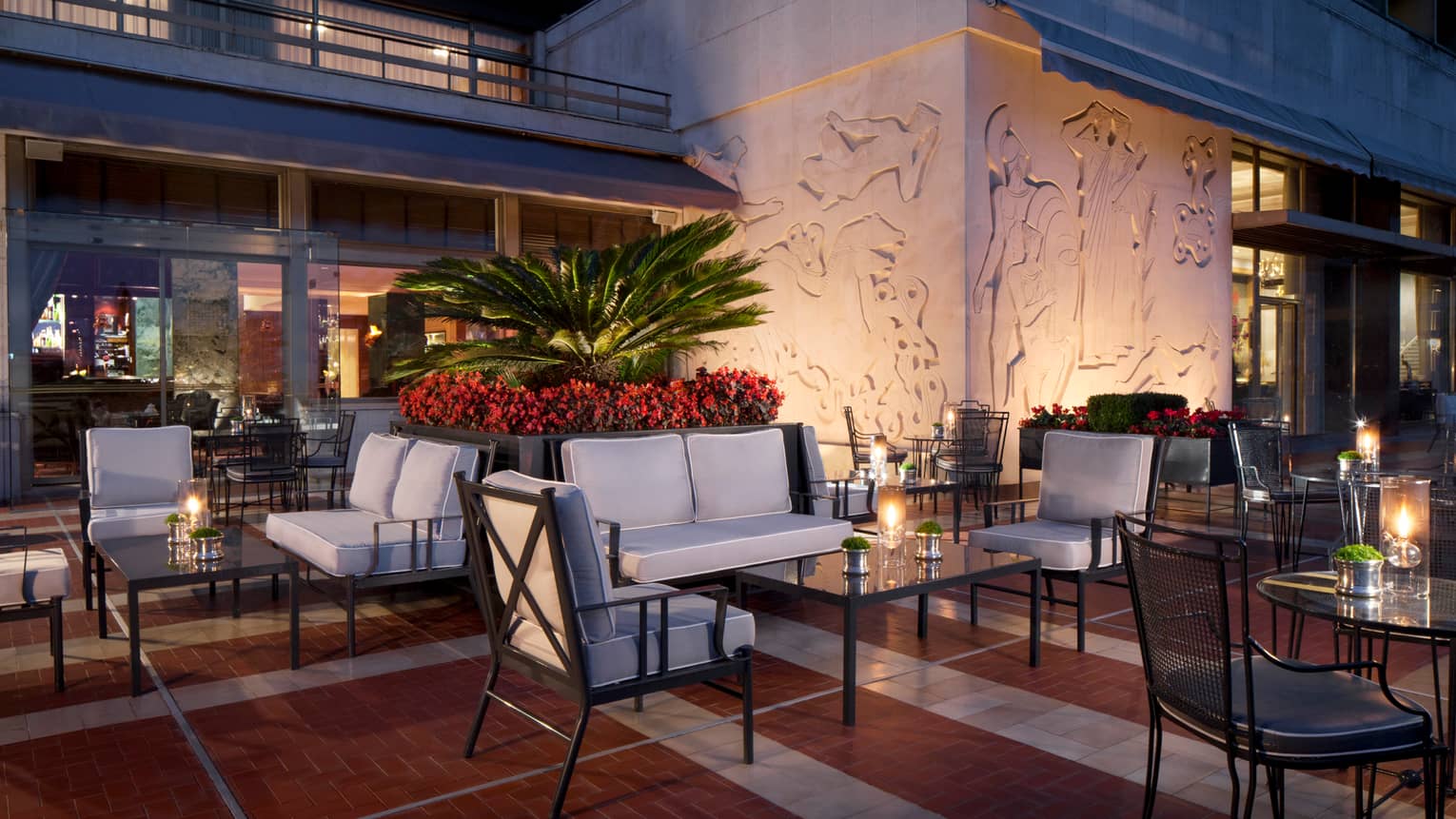 Ritz Bar outdoor patio lounge at night with cushioned chairs and loveseats around candle-lit cocktail tables