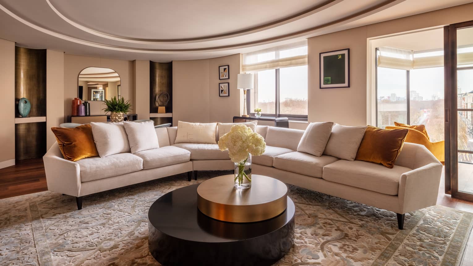 Hyde Park Suite living room with beige sectional, round coffee table with white flowers in vase