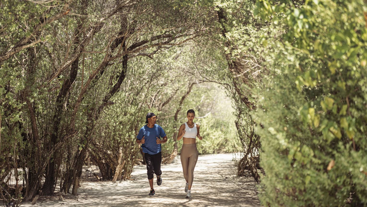 Man and woman jog through copse of trees during Kuda CrossFit