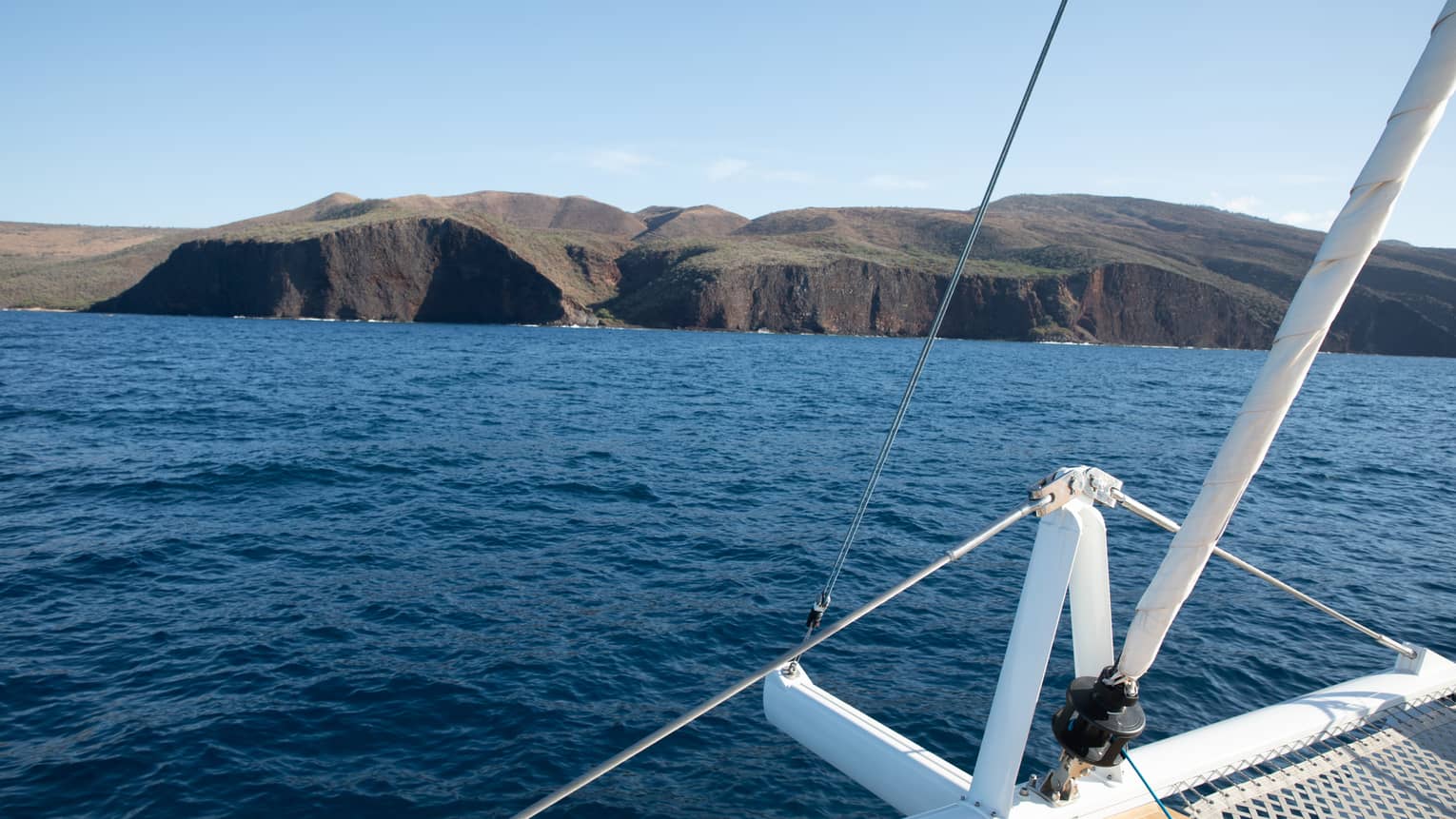 The edge of a boat looking out and land and water.