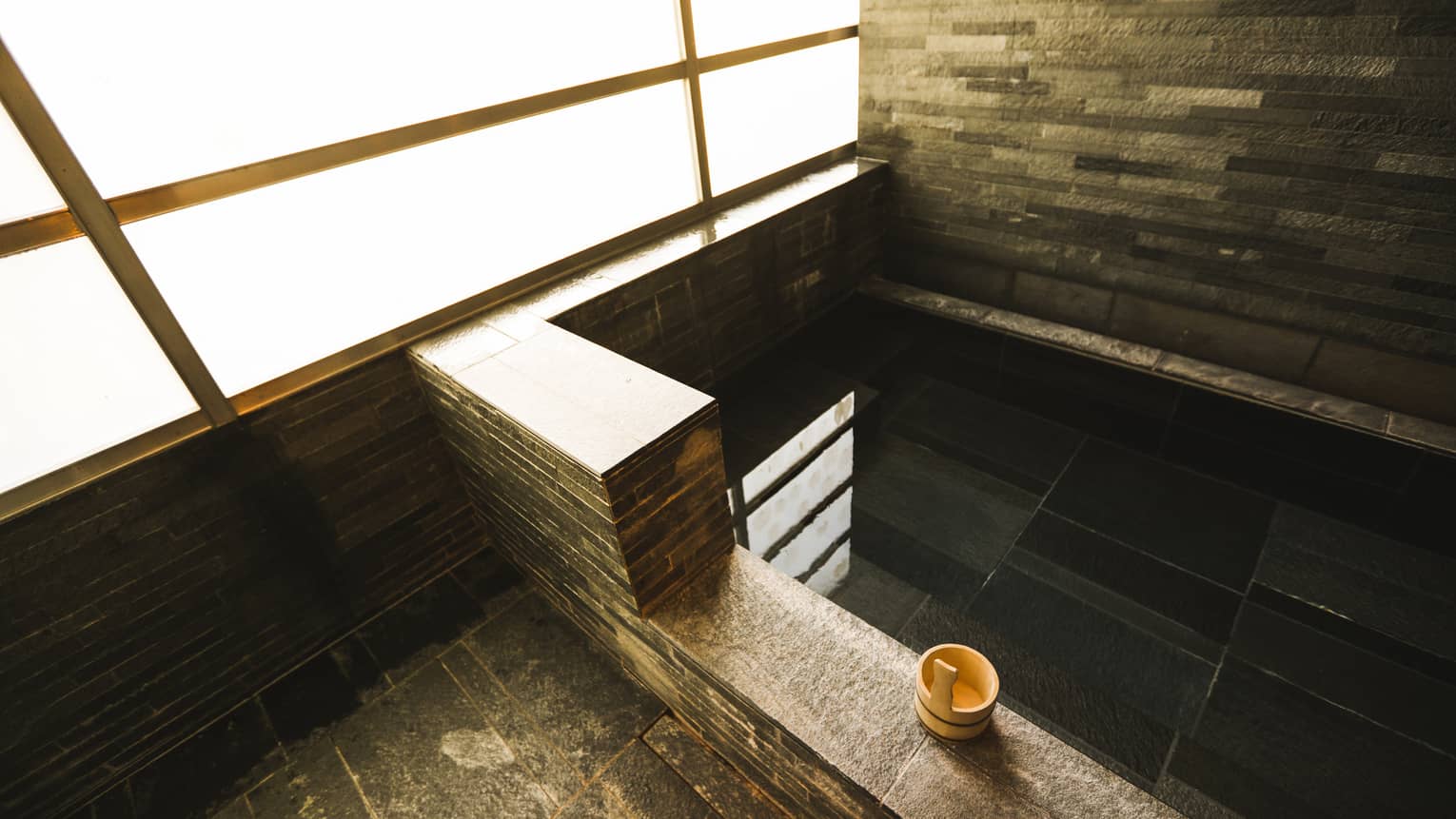 Rectangular black granite spa tub, small wood bowl on ledge