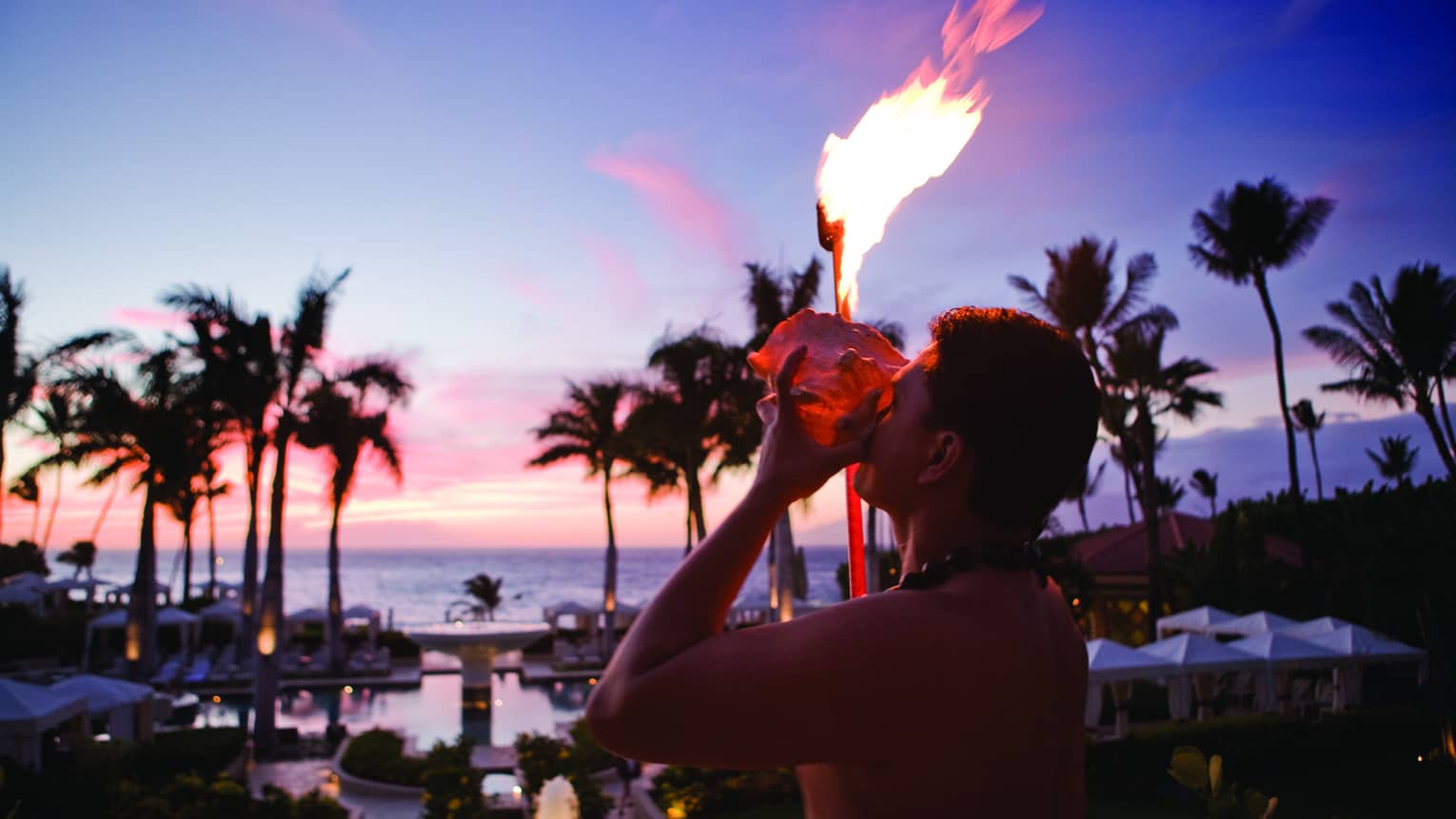 A staff member lights a torch with a view of the ocean