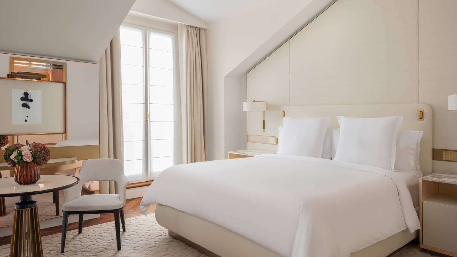 Contemporary hotel room with white king bed and beige-coloured walls and carpet