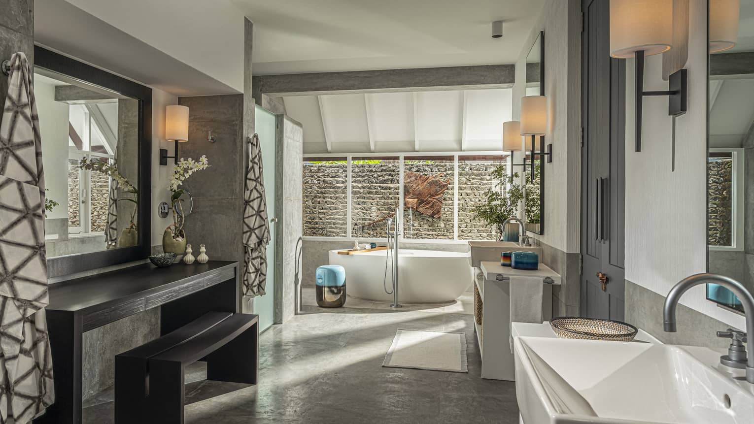 Large master bathroom with freestanding tub by window and wooden vanity