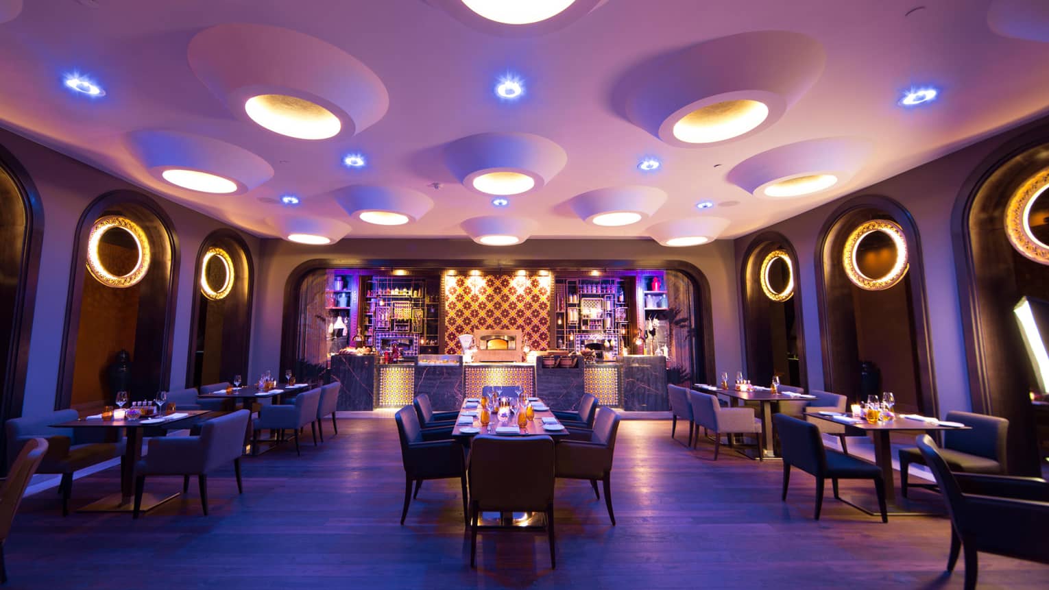 Candle-lit tables, chairs in Quattro dining room with large modern pot lights in white ceiling