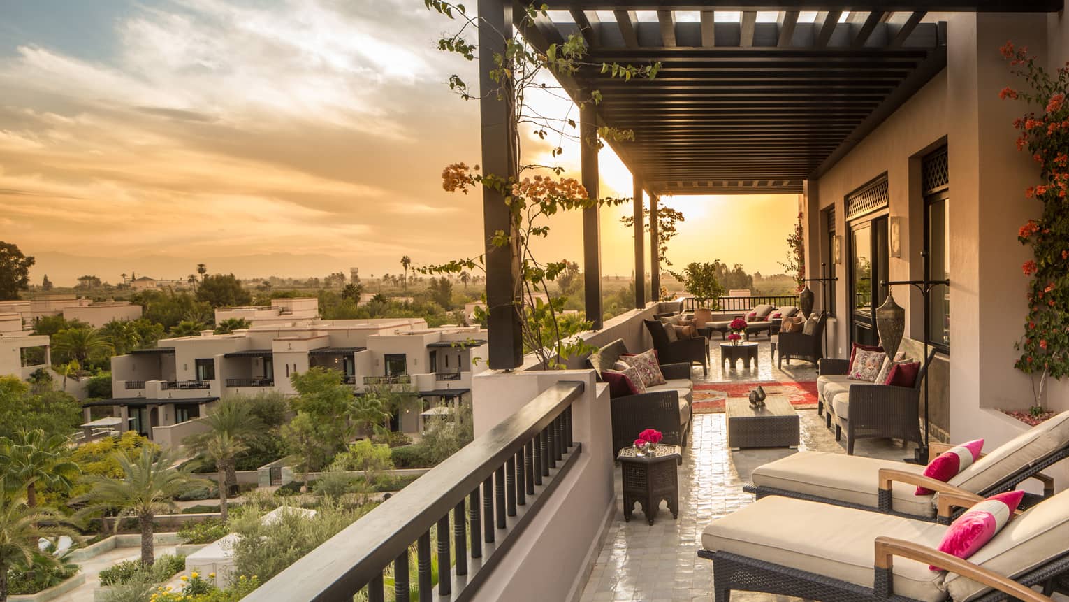 Moorish gardens below below long white hotel balcony with plush patio furniture 