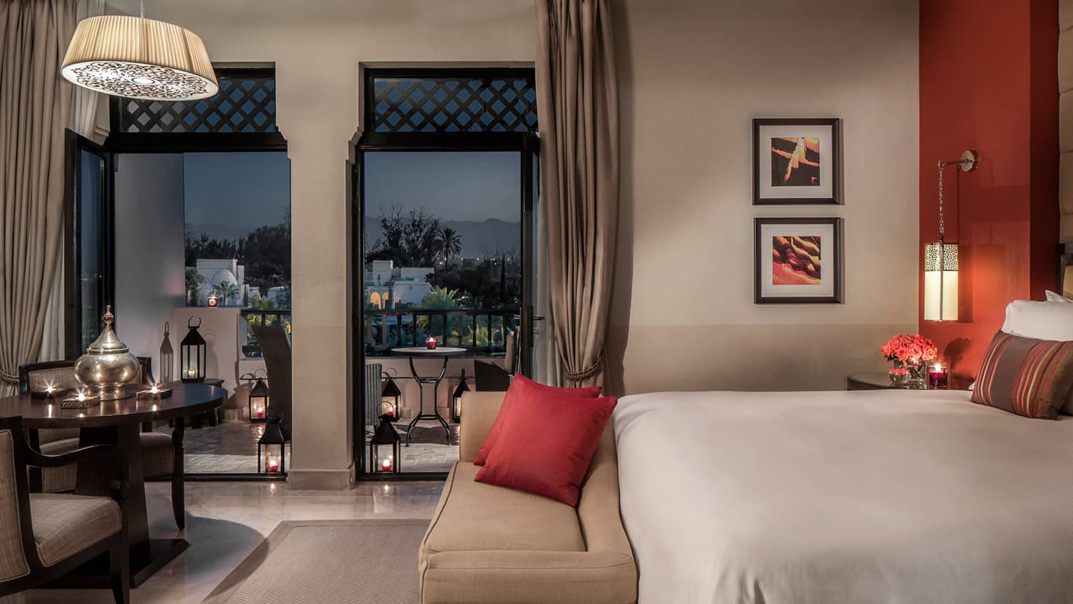 Pool Terrace Room at night with bed, plush bench, candle-lit table and lanterns on patio