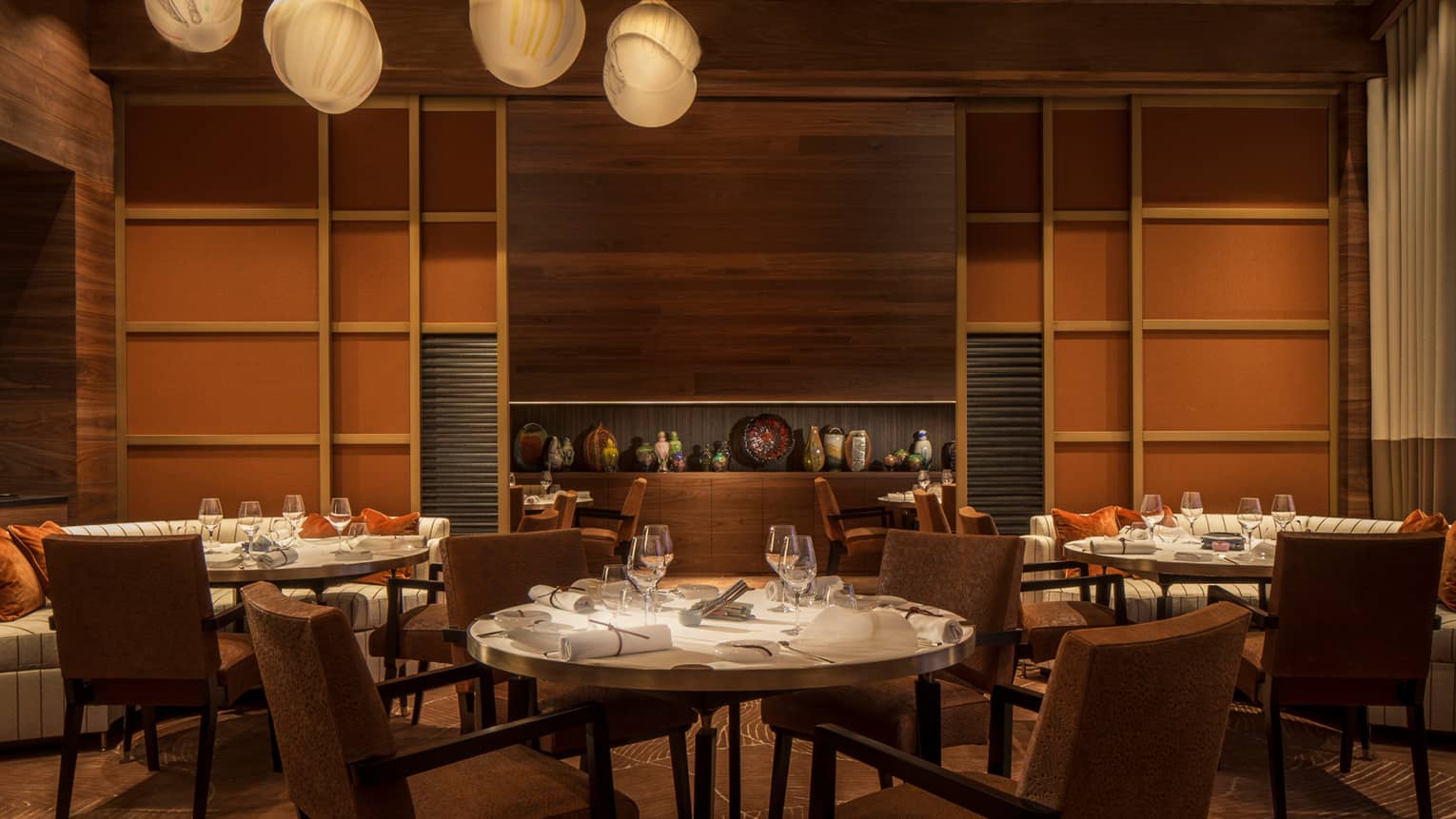 Le 1929 dining tables, chairs, wood panel walls, shelves with vases, sculptures