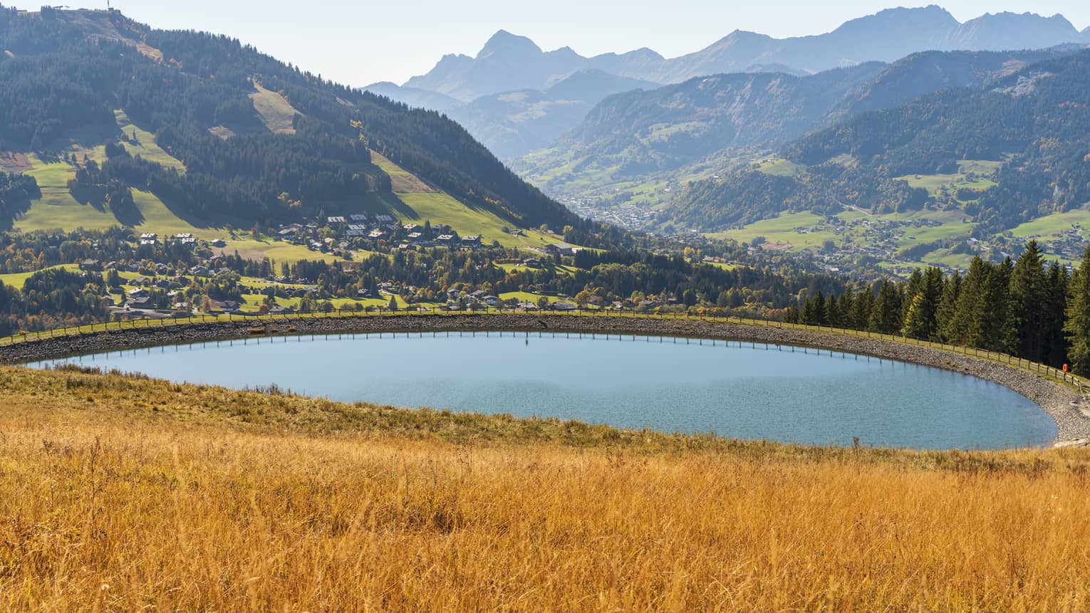 Oval lake at the foot of the Alps in autumn