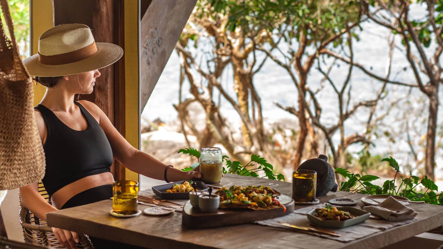 Woman sits at outdoor restaurant table overlooking ocean