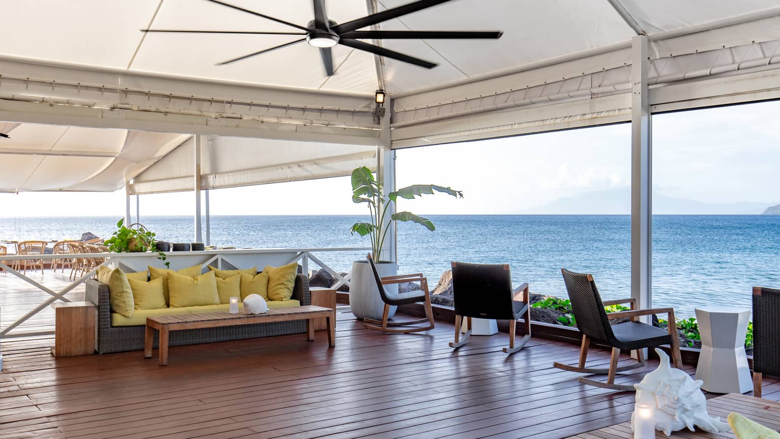 An outdoor dining area with a ceiling fan and ocean views