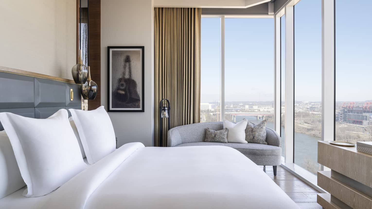 Bedroom with king bed, chaise and corner walls of windows