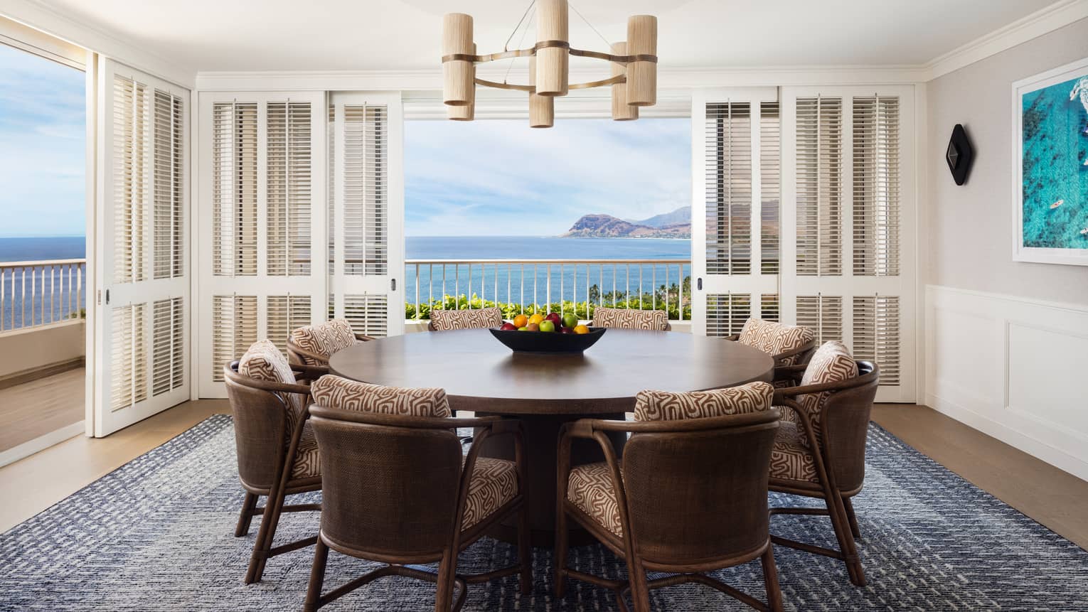 Dining room featuring a large circular table and eight chairs, and doors opening to ocean views on two sides