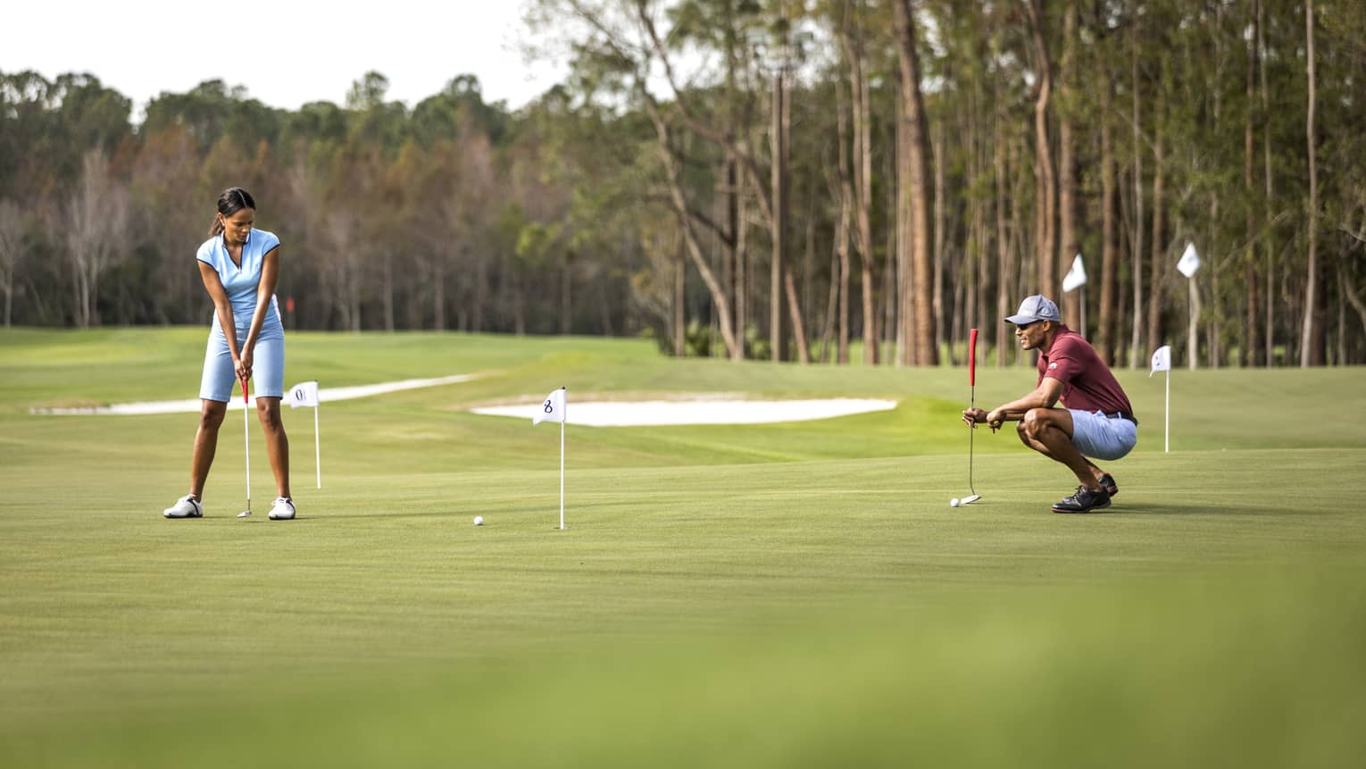 A woman playing golf makes a putt on the green 