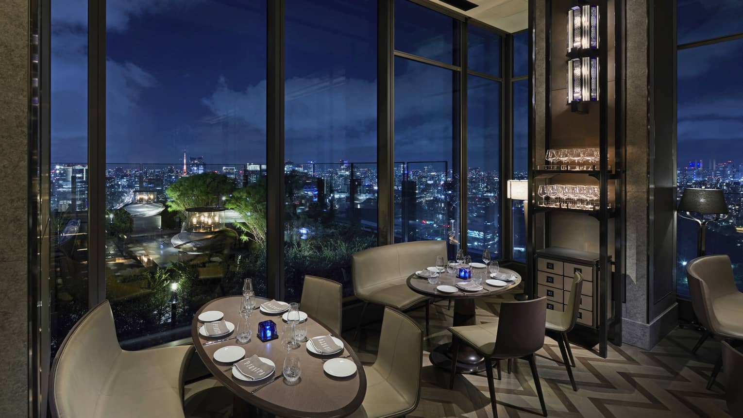 Curved leather booth overlooks the nighttime skyline, intimate lighting, floor-to-ceiling windows