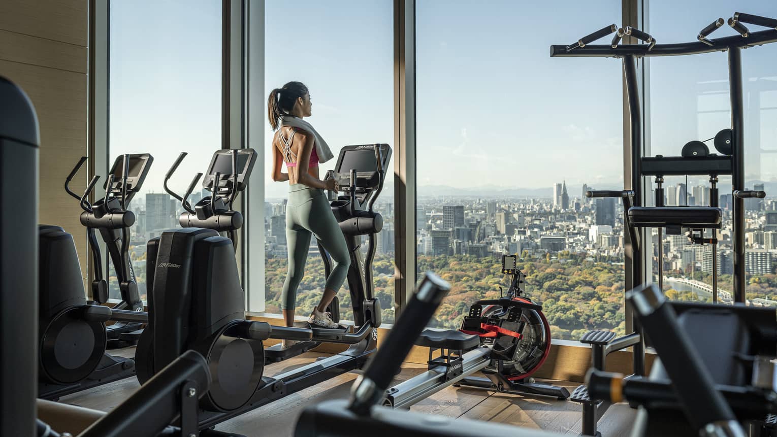 Woman on treadmill gazes out floor-to-ceiling windows of the fitness centre